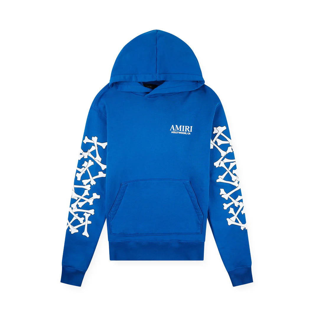 Blue AMIRI hoodie featuring white 'AMIRI HOLLYWOOD, CA' on chest and stacked bone graphics on both sleeves.