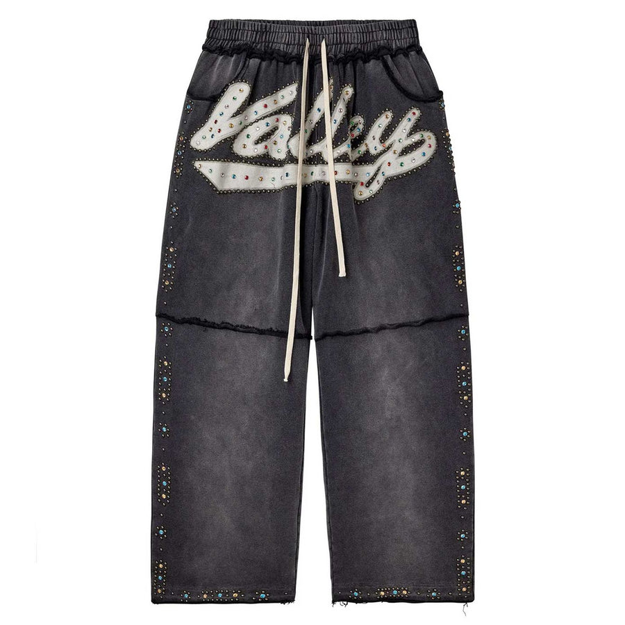 Washed black Vale Forever Skittles sweatpants, white drawstring, 'Vale' logo with colorful rhinestones, and studded legs.