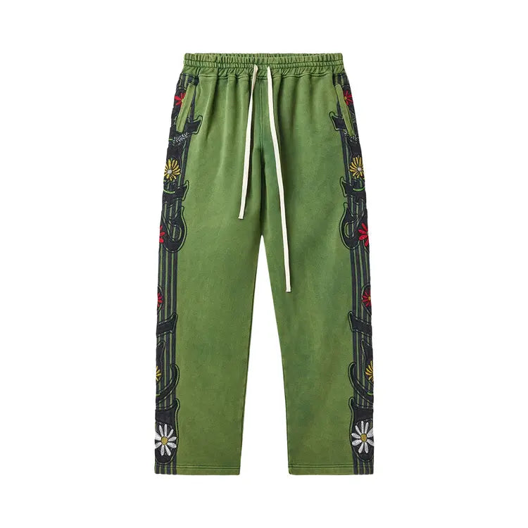 Faded green sweatpants with white drawstring and dark vertical side panels featuring red, yellow, & white flowers.