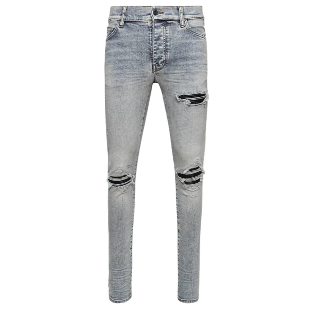 AMIRI MX1 skinny jeans in stone indigo wash, featuring large rips at thighs and knees backed by black fabric.