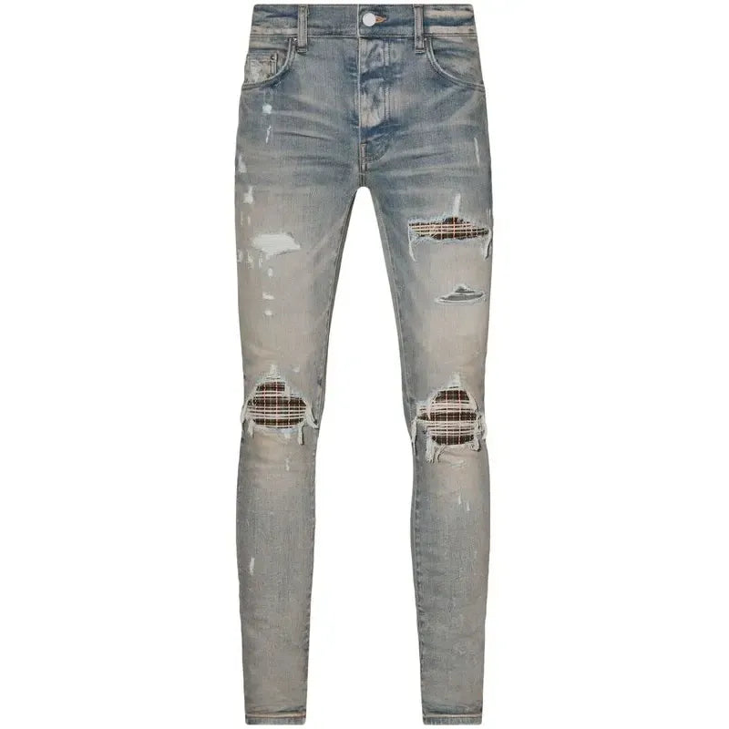 AMIRI MX1 Jean: Faded light blue distressed denim with rips revealing neon plaid patches at the knees and thigh.