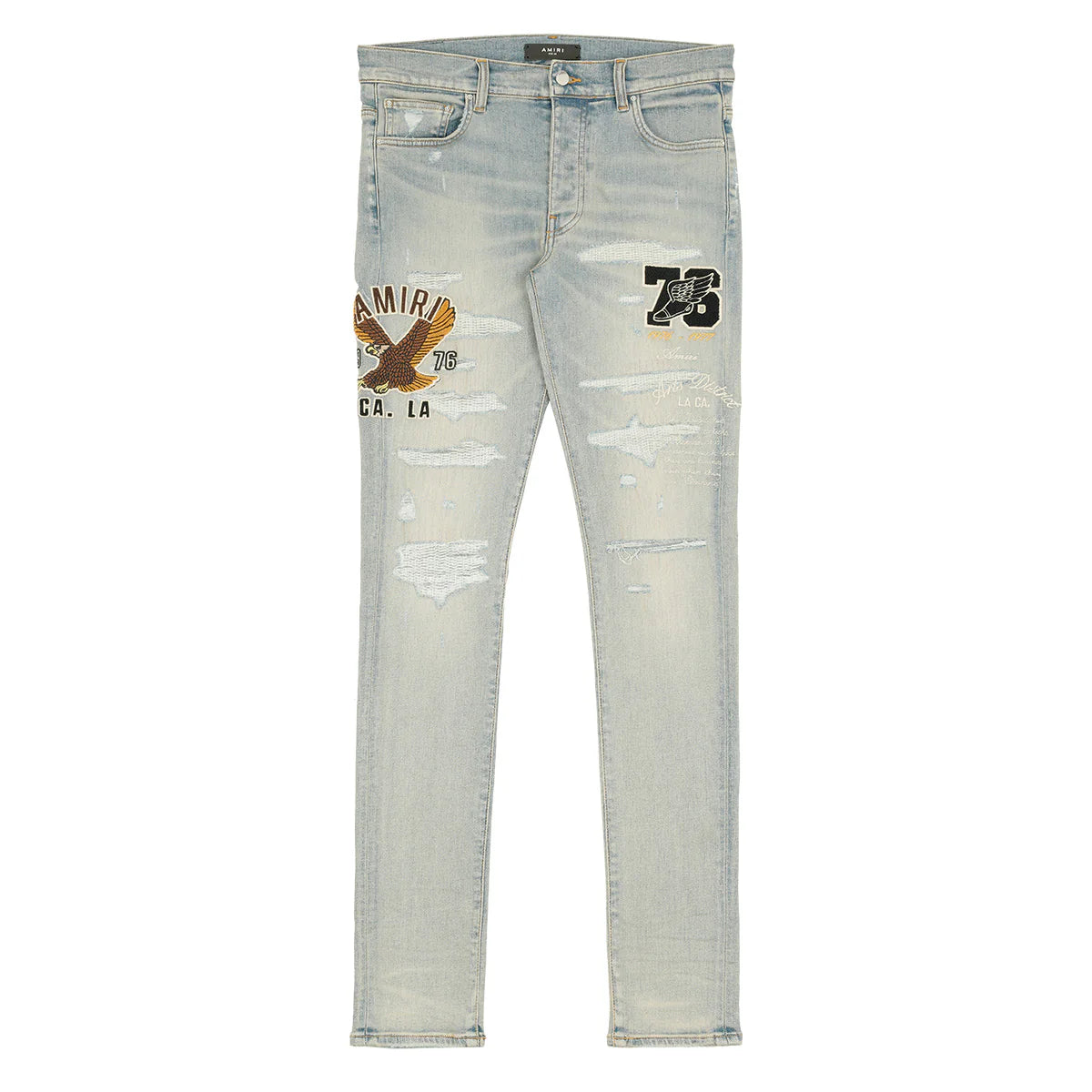 AMIRI light wash distressed jeans with eagle & "AMIRI 76" patch on left leg, "73" winged shoe on right.