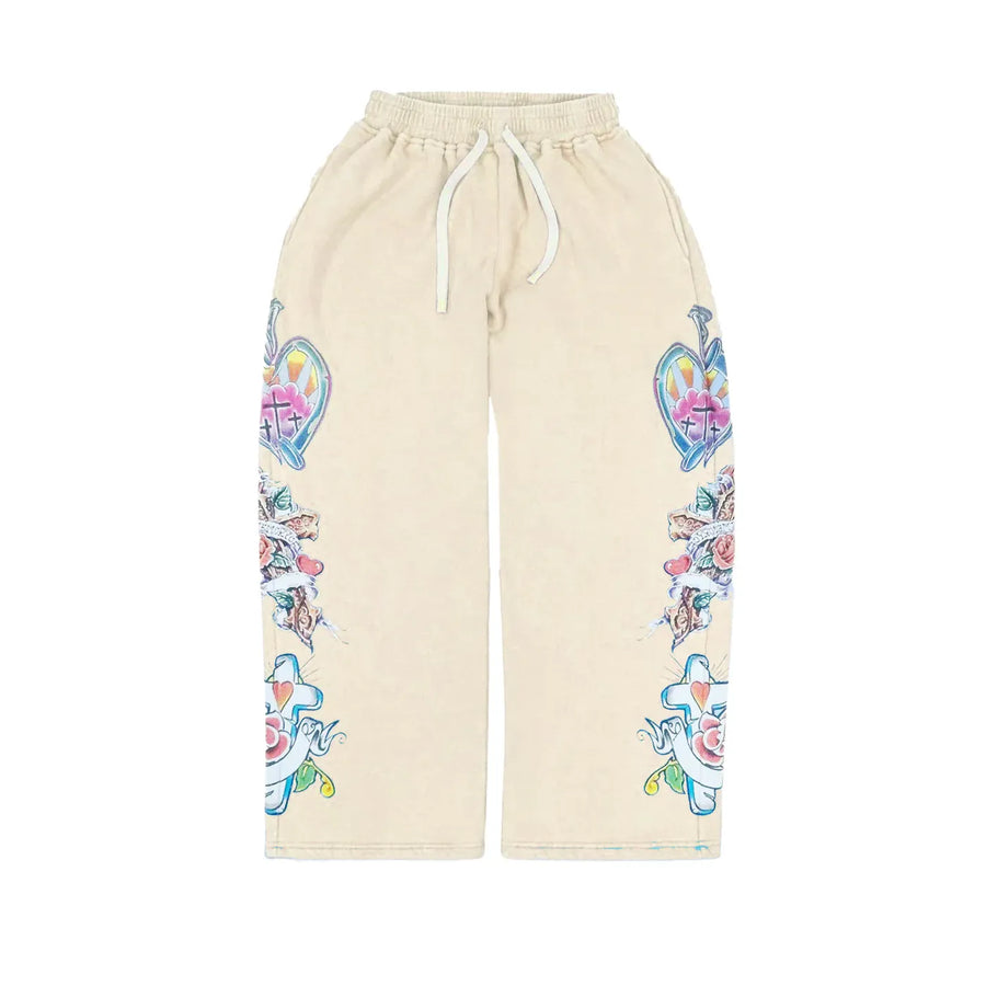 Cream sweatpants with white drawstring. Vibrant tattoo-style hearts, crosses, nails, & roses decorate both legs.