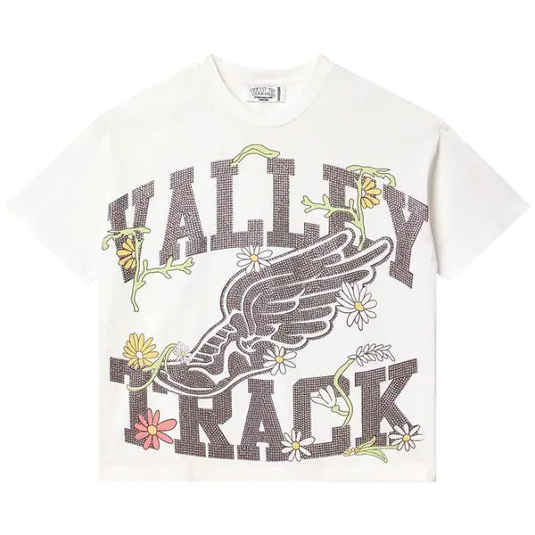 Vale Forever white tee with dark, studded "VALLEY TRACK" text, winged shoe, and colorful flower & vine graphics.