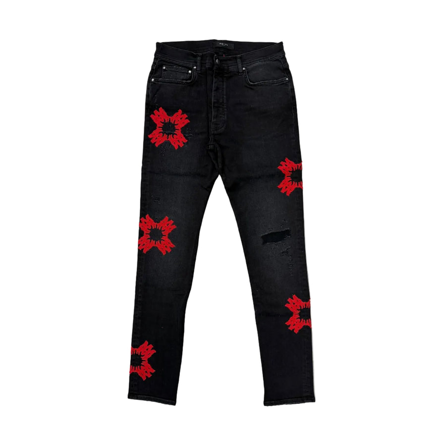 AMIRI Vintage Black distressed jeans with red quad appliqués on thighs, knees, and shins.